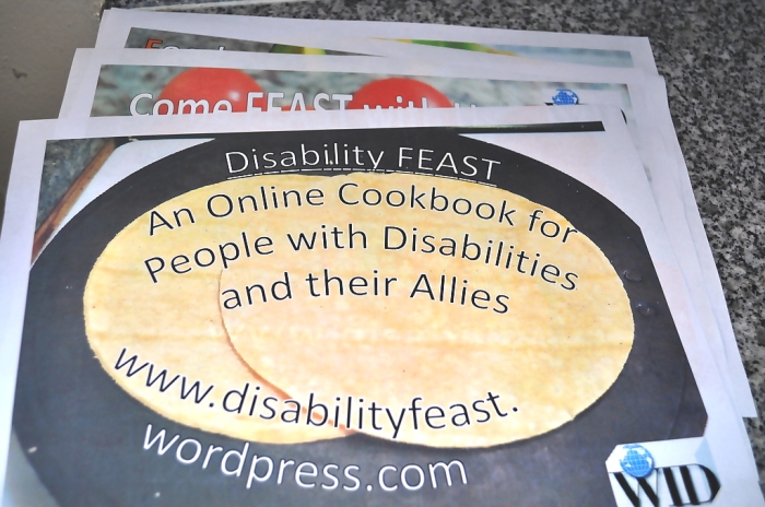 A stack of colorful flyers, the one on top advertising Disability FEAST with a picture of tortillas